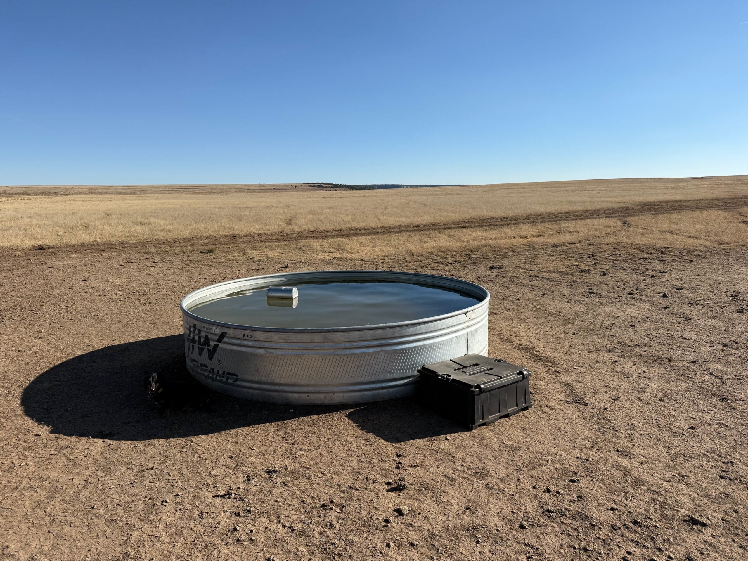 Metal water tank with a solar-powered deicer in a desert landscape with clear blue sky